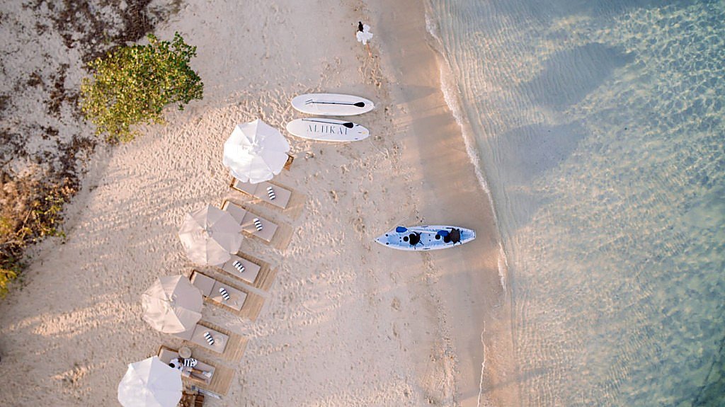 Aerial view of Aliikai Voyage beach club with loungers, paddleboards and a kayak
