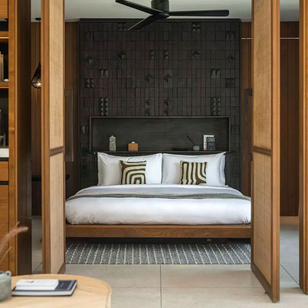 Suite bedroom with a carved timber headboard at Cap Karoso