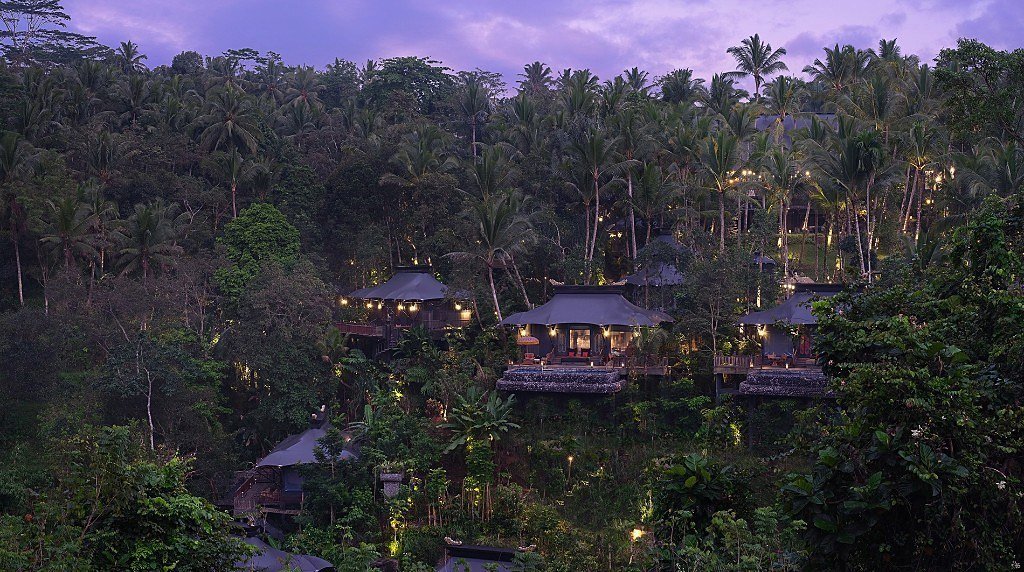 Tents of Capella Ubud lit across the jungle valley at dusk