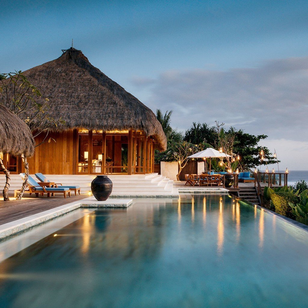 Villa pool and thatched pavilion lit at dusk at Nihi Sumba